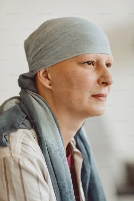 Une femme portant un foulard regarde au loin, sereine.